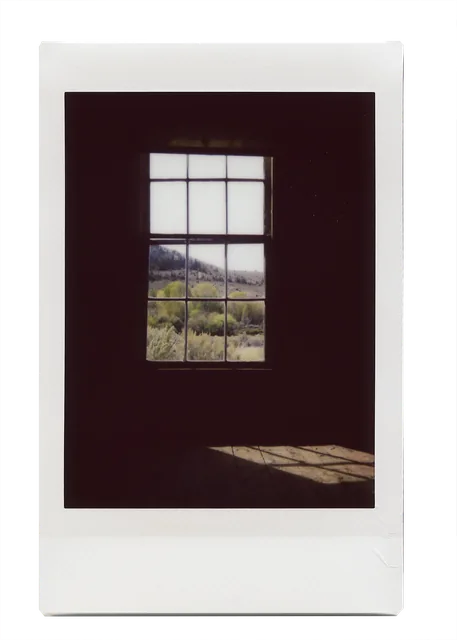 Instax Mini print of a window in an old cabin